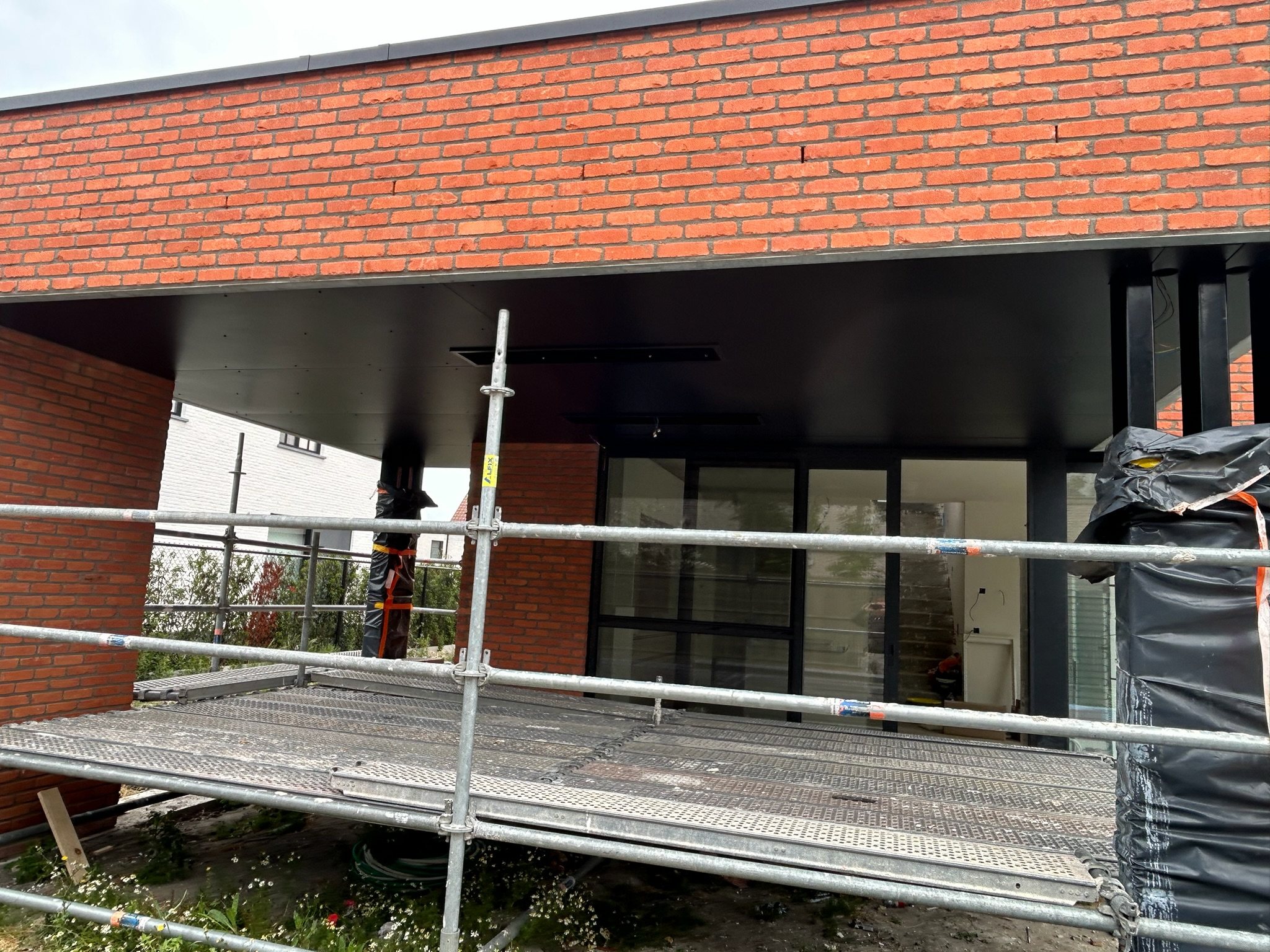 Zwart plafond onder een overdekt terras van een nieuwbouw in De Haan, tijdens de werken