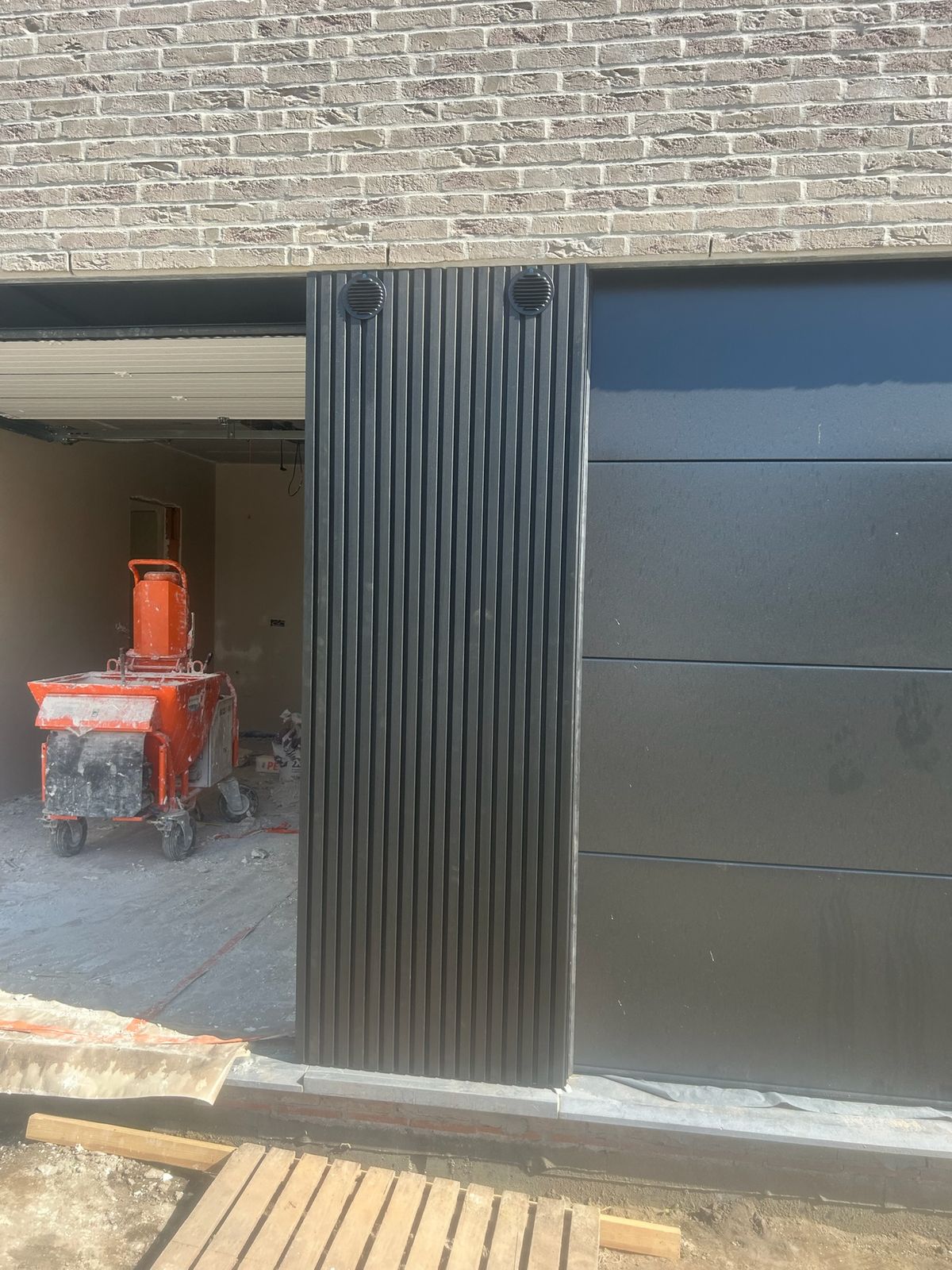 Strook zwarte gevelbekleding tussen een opening en zwarte panelen aan een woning in Torhout.