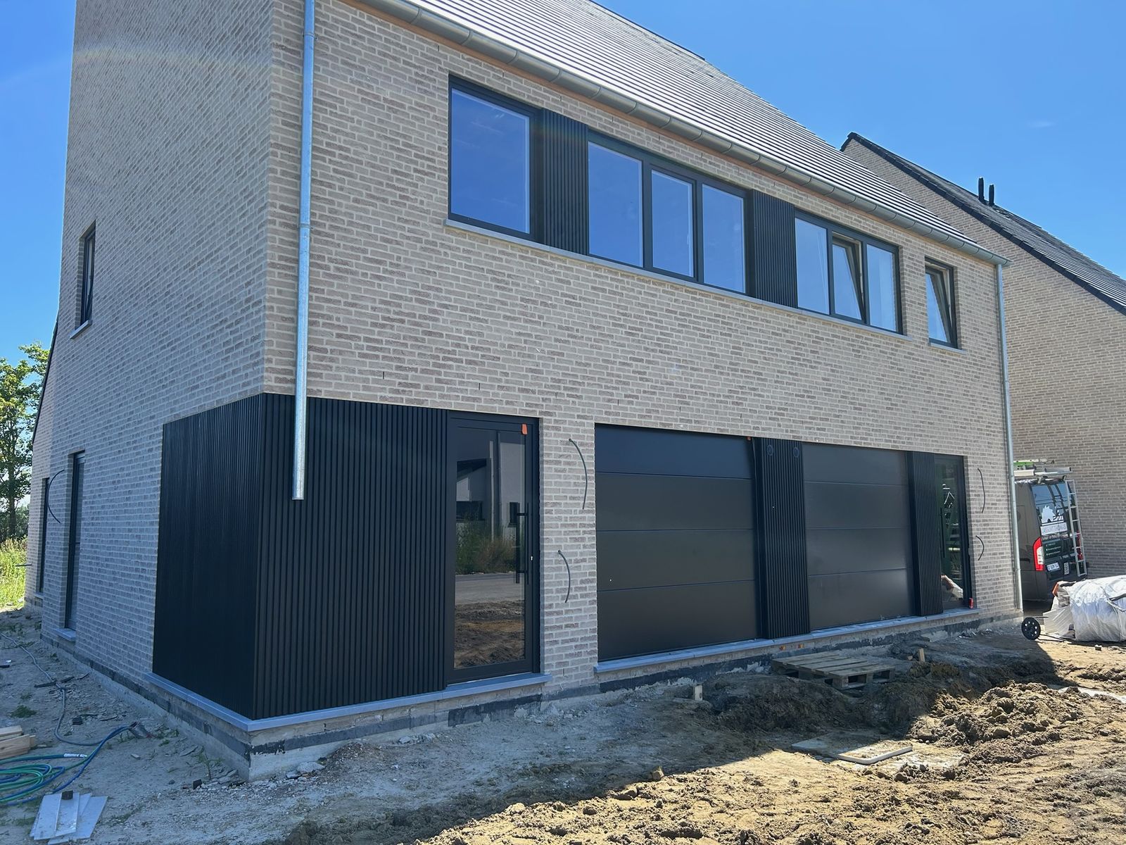 Nieuwbouwwoning in lichte baksteen met zwarte gevelbekleding op de benedenverdieping in Torhout.