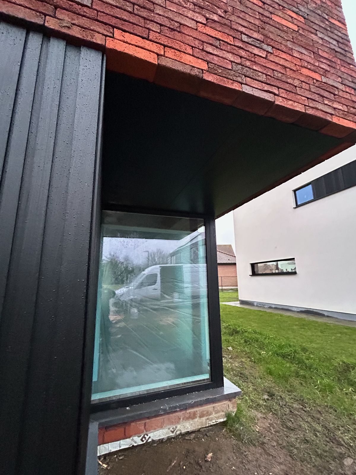 Zwarte gevelbekleding en zwart plafond bij een overdekte hoek met raam in Wingene.