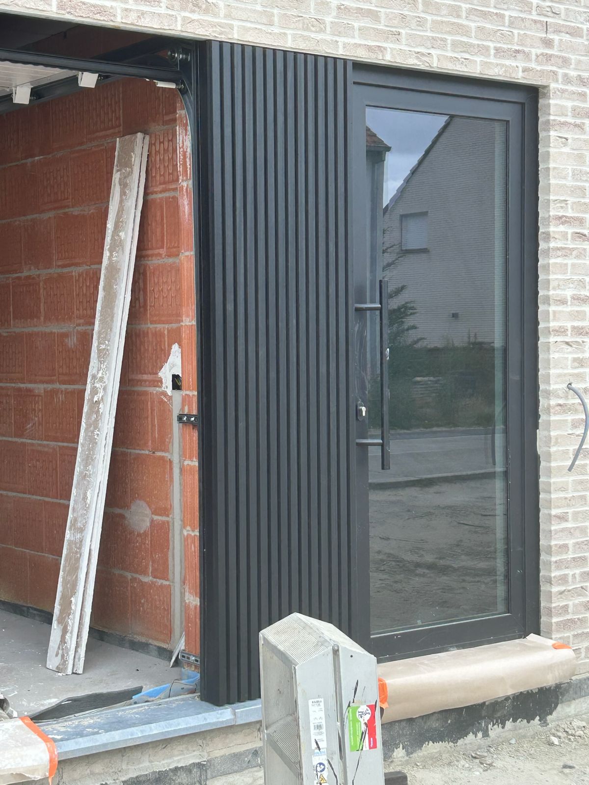 Zwarte verticale gevelbekleding naast een zwarte voordeur van een nieuwbouw in Torhout.