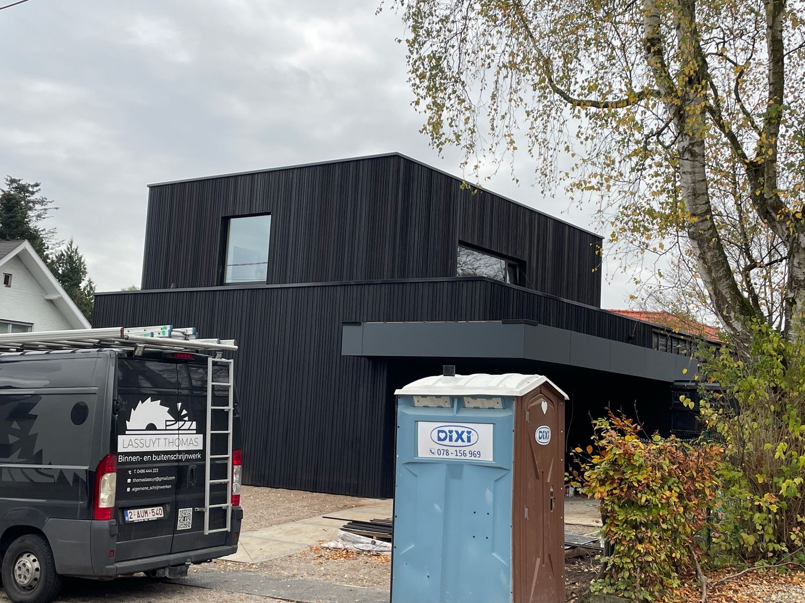 Kubusvormige woning met zwarte houten gevelbekleding en luifel tijdens de oplevering in Overijse.